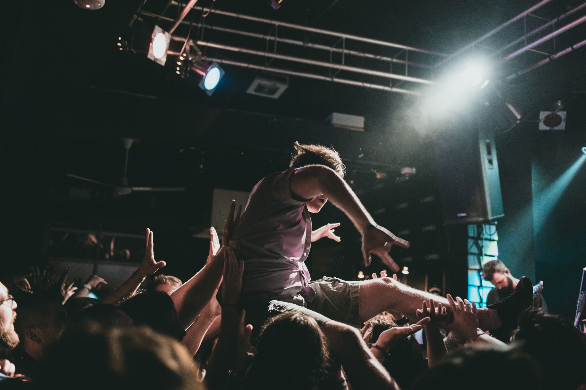 A fan crowd surfing over raised arms at a live show