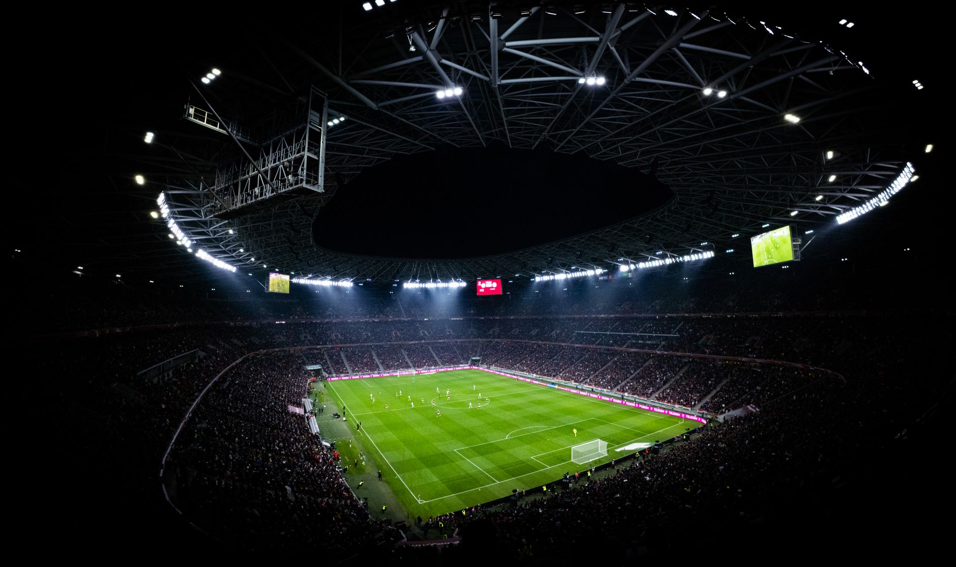 Aerial view of a full stadium under floodlights at night, every tier occupied